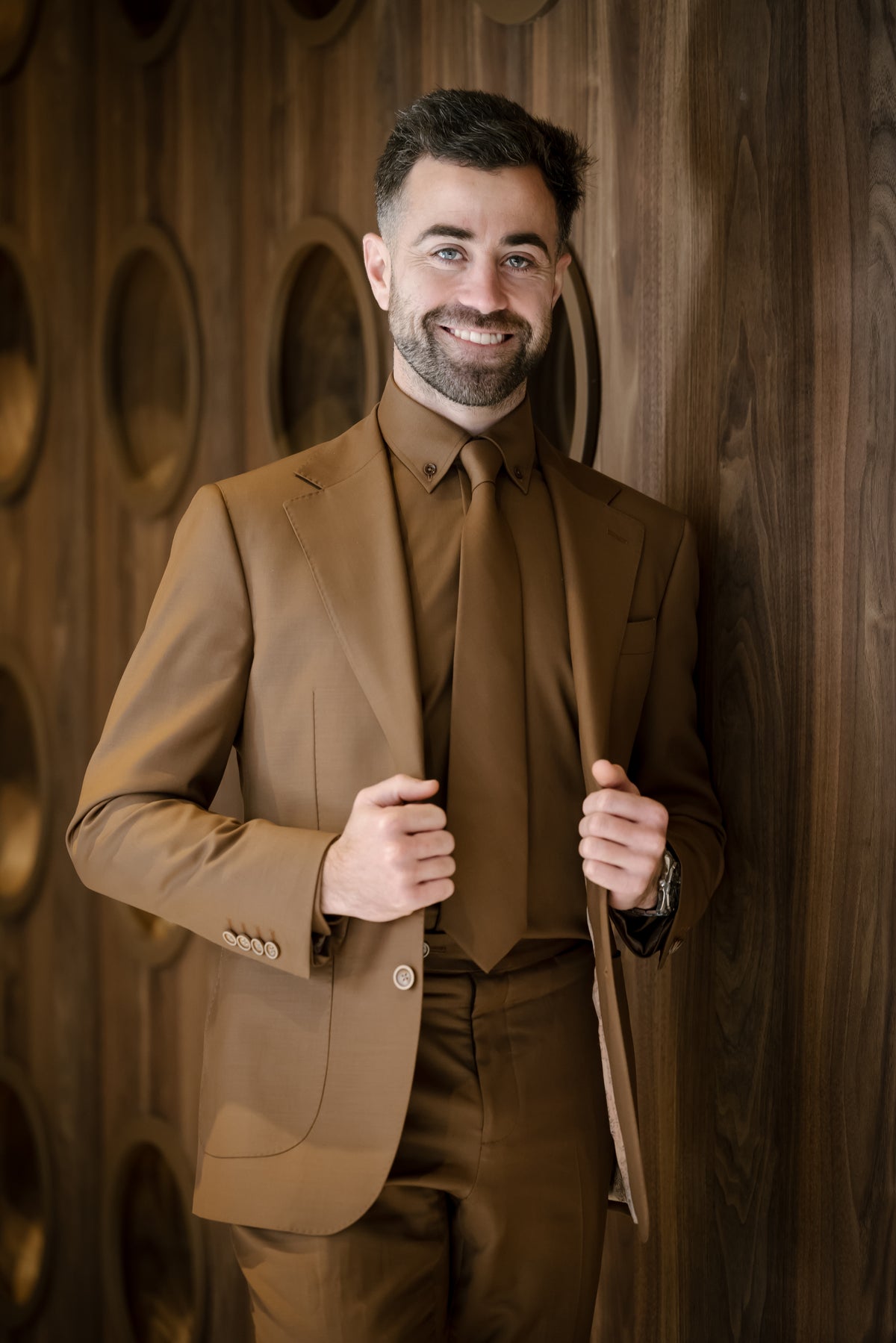 Dylan the founder of The Tailors Lounge wearing a custom tailored suit which is tone on tone using the colour rust. This is matched with a rust tie
